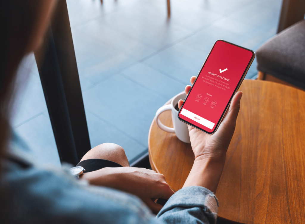 Person holding phone with screen displaying 'payment confirmed'